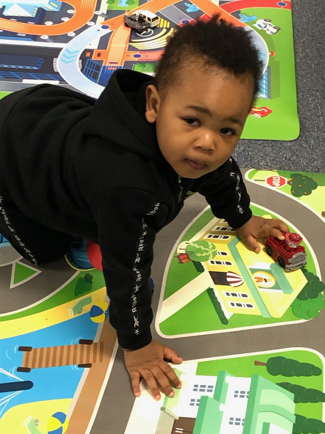Toddler playing with toy cars at Munchkinland daycare